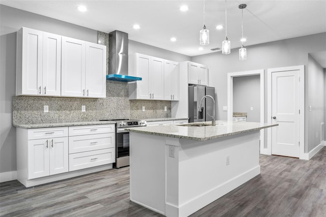 kitchen with sink, appliances with stainless steel finishes, a kitchen island with sink, white cabinets, and wall chimney exhaust hood