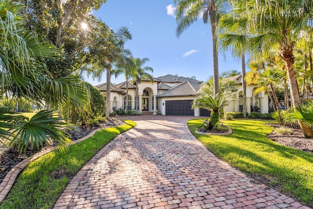 mediterranean / spanish house featuring a garage and a front lawn