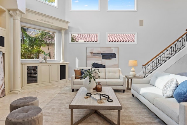 living room featuring a towering ceiling, ornate columns, and a healthy amount of sunlight