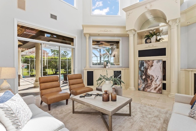 living room with ornate columns, a high ceiling, and plenty of natural light