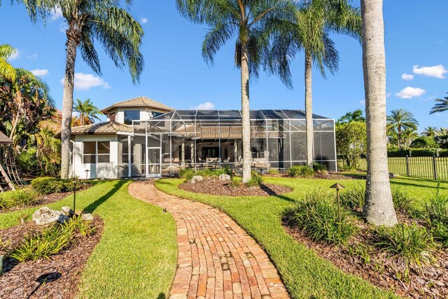 back of property with glass enclosure and a yard