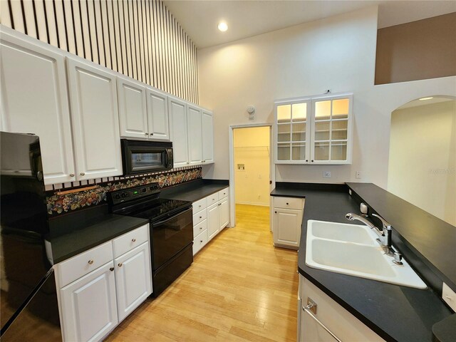 kitchen featuring black appliances, white cabinets, and a high ceiling