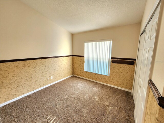 empty room with a textured ceiling and carpet