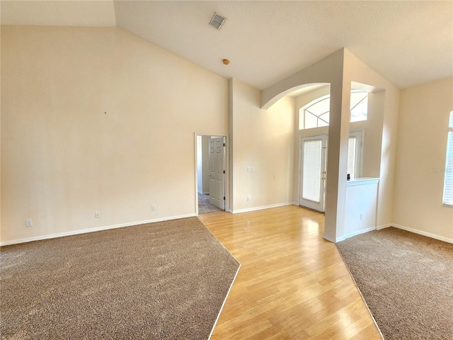 unfurnished living room with high vaulted ceiling and light wood-type flooring