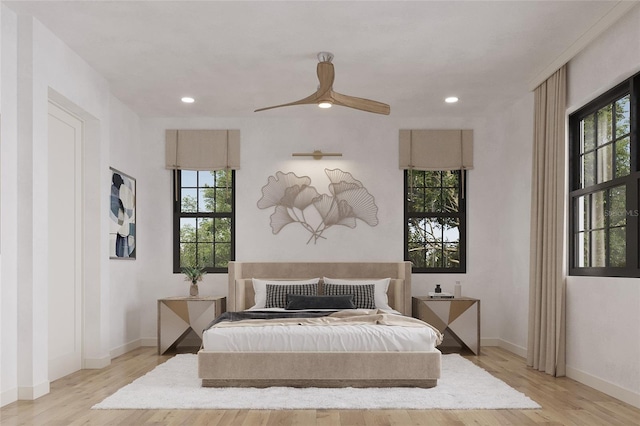 bedroom featuring ceiling fan, light hardwood / wood-style flooring, and multiple windows