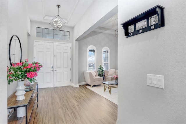 foyer entrance featuring a tray ceiling, hardwood / wood-style flooring, a towering ceiling, and an inviting chandelier