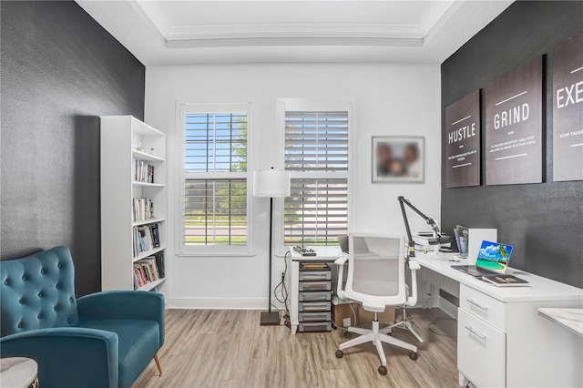 office featuring ornamental molding, light hardwood / wood-style floors, and a raised ceiling