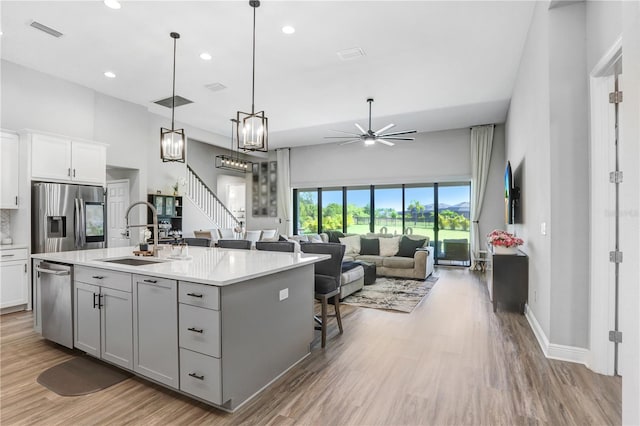 kitchen featuring decorative light fixtures, stainless steel appliances, a center island with sink, and wood-type flooring