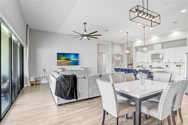 dining space with ceiling fan with notable chandelier and light hardwood / wood-style floors