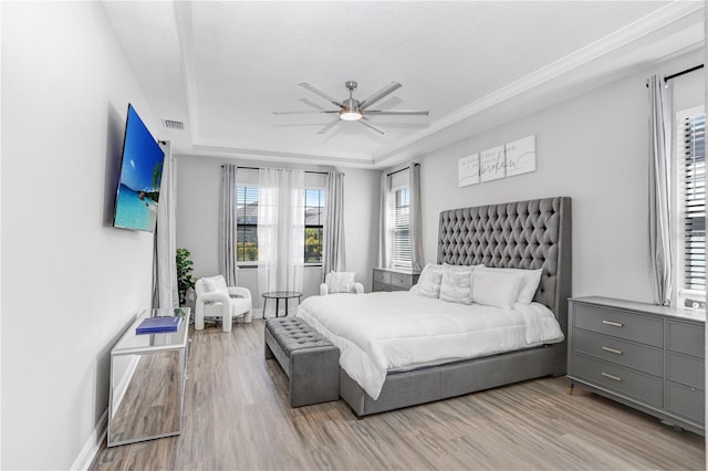 bedroom with a tray ceiling, light wood-type flooring, and ceiling fan