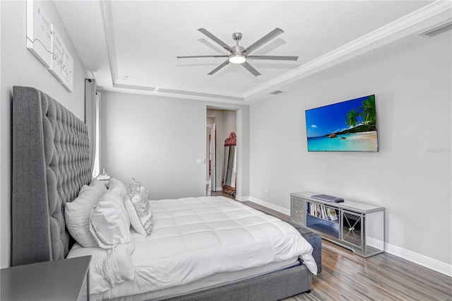 bedroom with wood-type flooring, ceiling fan, and a raised ceiling