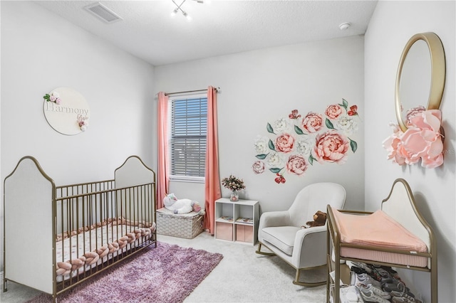 carpeted bedroom featuring a crib and a textured ceiling