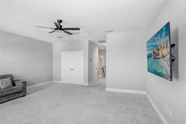 living area featuring a textured ceiling, ceiling fan, and carpet floors