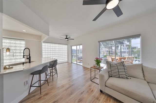 living room featuring light hardwood / wood-style floors, sink, and ceiling fan