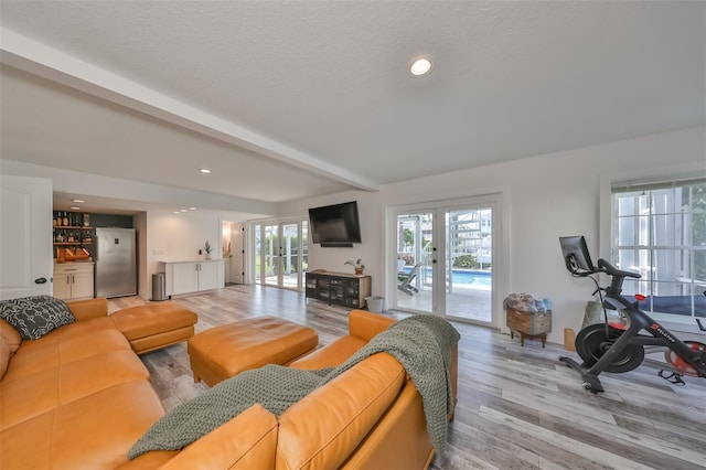 living room featuring a textured ceiling, beam ceiling, french doors, and light hardwood / wood-style floors