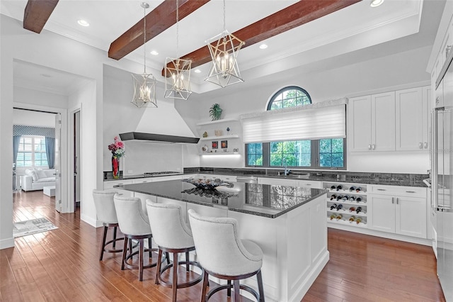 kitchen featuring stainless steel gas stovetop, a center island, white cabinets, decorative light fixtures, and dark hardwood / wood-style flooring