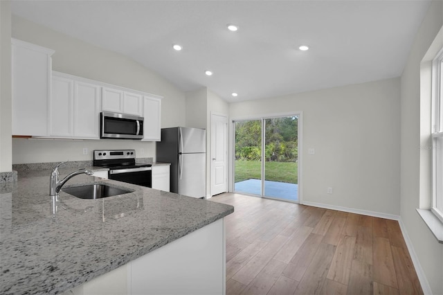 kitchen featuring light stone counters, white cabinetry, light wood-type flooring, appliances with stainless steel finishes, and sink