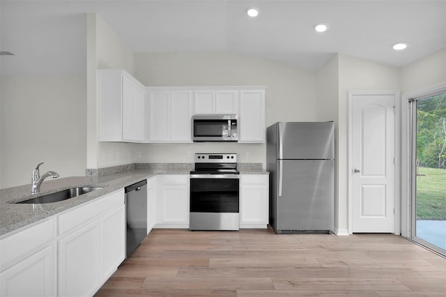 kitchen with stainless steel appliances, white cabinets, lofted ceiling, and sink