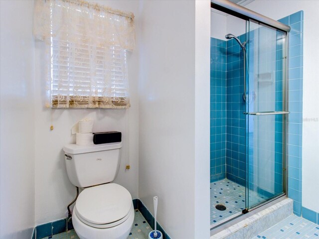 bathroom with a shower with shower door, toilet, and tile floors