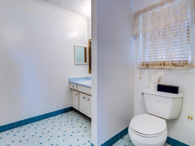 bathroom with tile flooring, ornamental molding, a textured ceiling, vanity, and toilet