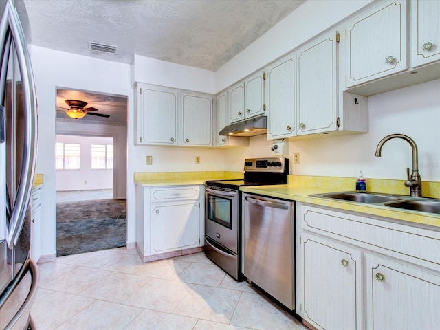 kitchen with appliances with stainless steel finishes, sink, ceiling fan, and light tile flooring