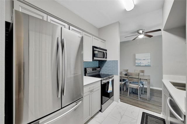 kitchen with light tile flooring, stainless steel appliances, ceiling fan, tasteful backsplash, and white cabinetry