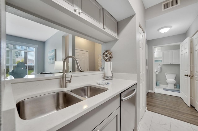 kitchen featuring gray cabinets, sink, light hardwood / wood-style floors, and stainless steel dishwasher