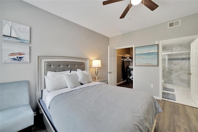 bedroom with a walk in closet, dark wood-type flooring, ensuite bath, a closet, and ceiling fan