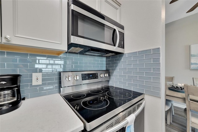 kitchen with white cabinetry, tasteful backsplash, ceiling fan, and stainless steel appliances