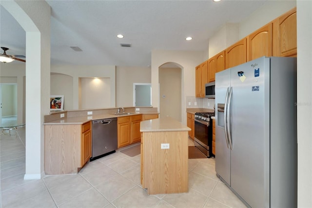 kitchen with ceiling fan, light tile floors, a center island, sink, and appliances with stainless steel finishes