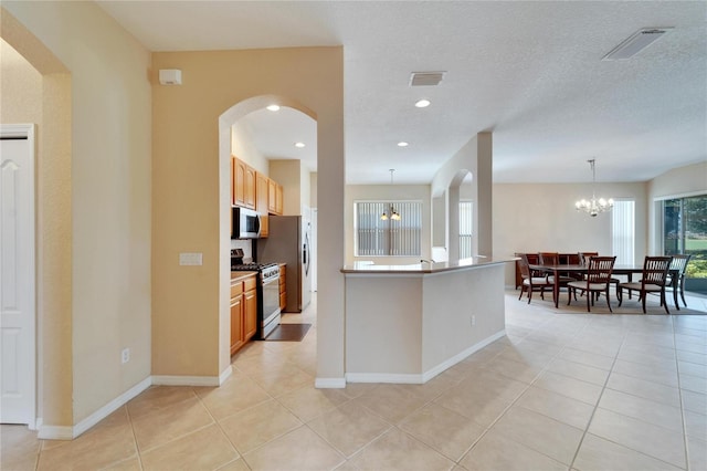 kitchen featuring hanging light fixtures, a textured ceiling, appliances with stainless steel finishes, a chandelier, and light tile floors