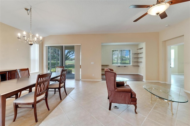 tiled dining room featuring ceiling fan with notable chandelier