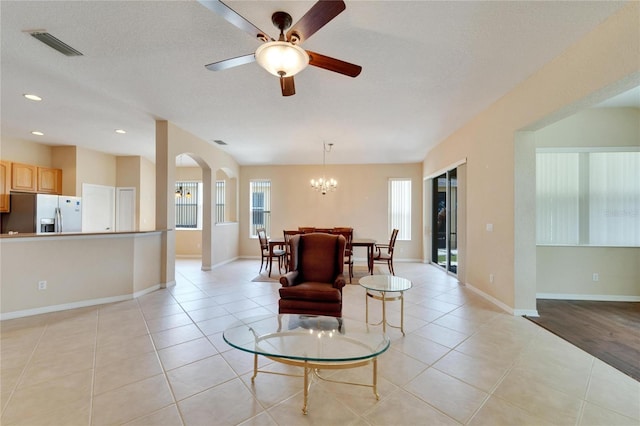 living room with a textured ceiling, light wood-type flooring, and ceiling fan with notable chandelier