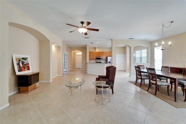 tiled living room with ceiling fan with notable chandelier