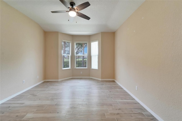 empty room with ceiling fan, a textured ceiling, and light wood-type flooring