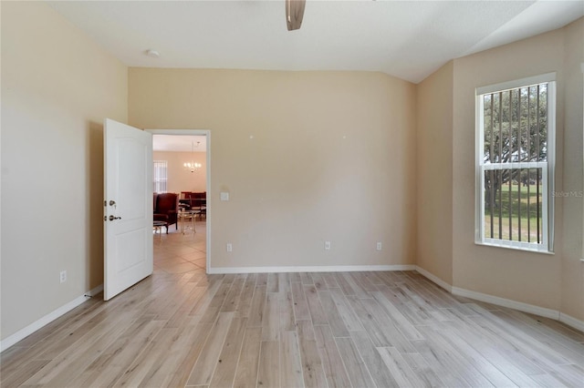 unfurnished room with a wealth of natural light, an inviting chandelier, and light hardwood / wood-style floors