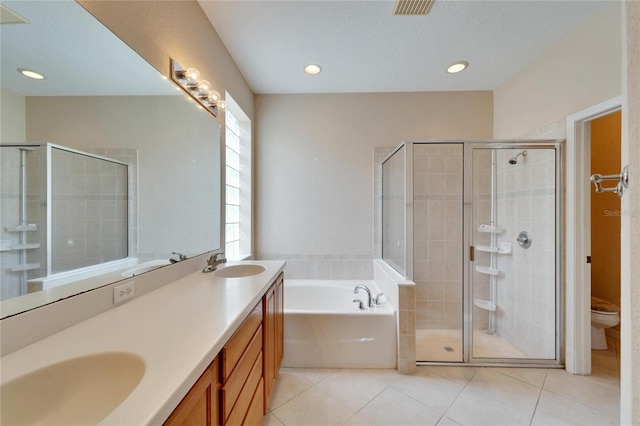 full bathroom with tile flooring, independent shower and bath, a textured ceiling, dual bowl vanity, and toilet