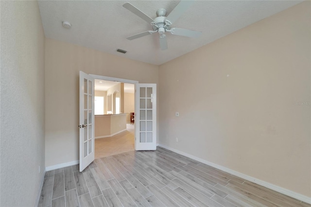 spare room with light wood-type flooring, french doors, and ceiling fan