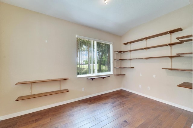 spare room featuring dark hardwood / wood-style floors and vaulted ceiling