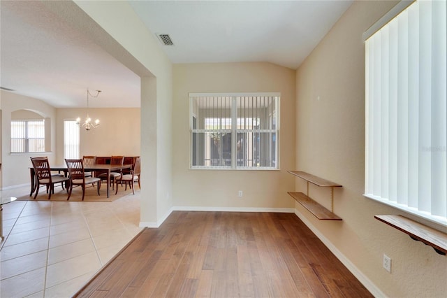 tiled spare room with an inviting chandelier and lofted ceiling