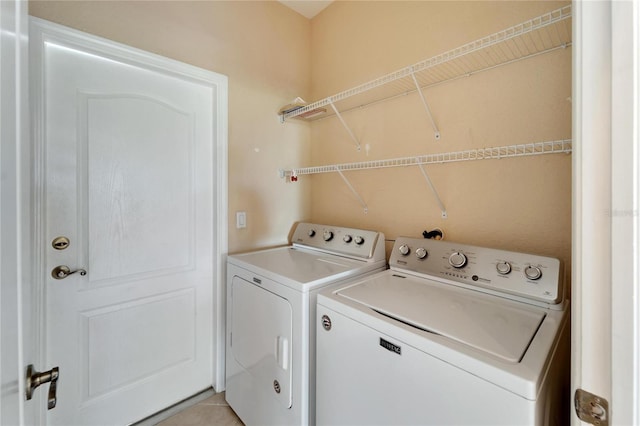 laundry room featuring washer and dryer and light tile floors