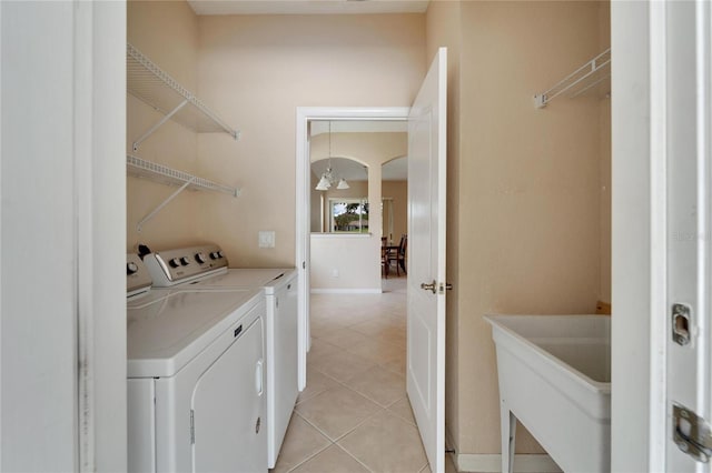 laundry area featuring sink, washer and dryer, and light tile floors