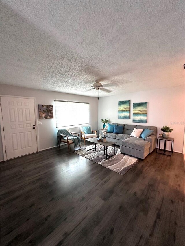 living room with a textured ceiling, dark hardwood / wood-style floors, and ceiling fan