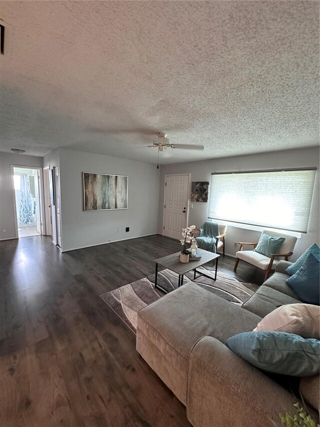 living room with ceiling fan, dark wood-type flooring, and a textured ceiling