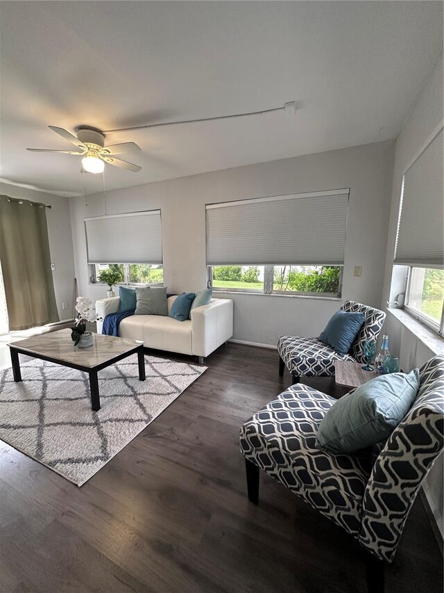 living room featuring dark wood-type flooring, ceiling fan, and plenty of natural light