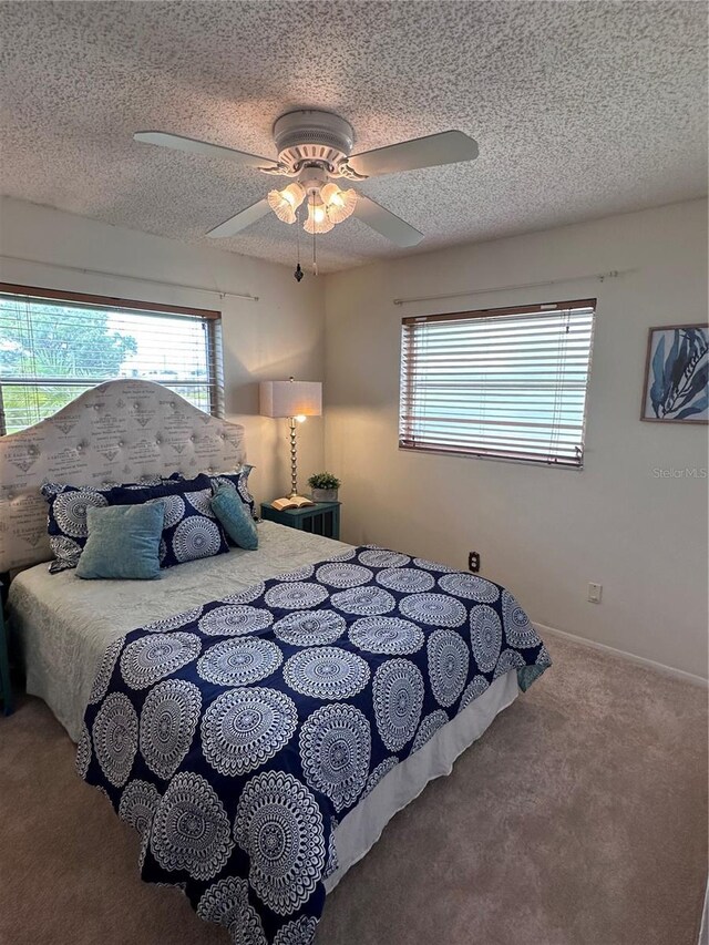 carpeted bedroom featuring ceiling fan and a textured ceiling