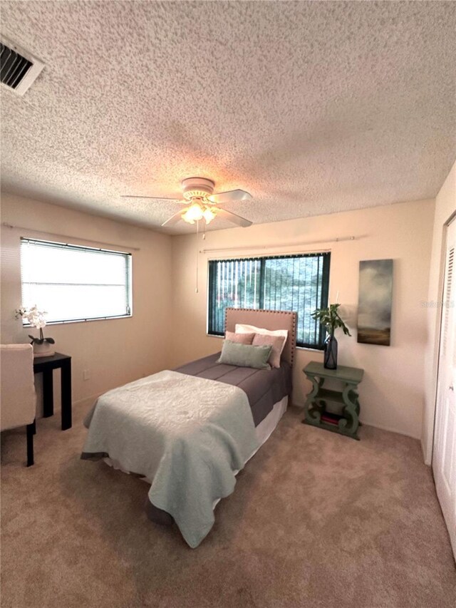 carpeted bedroom with a textured ceiling and ceiling fan