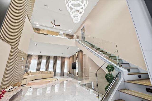 stairway featuring ceiling fan with notable chandelier