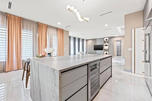 kitchen with a kitchen island, wine cooler, pendant lighting, and a kitchen breakfast bar