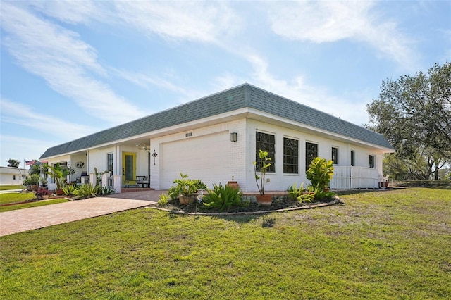 ranch-style home featuring a garage, a shingled roof, mansard roof, decorative driveway, and a front yard